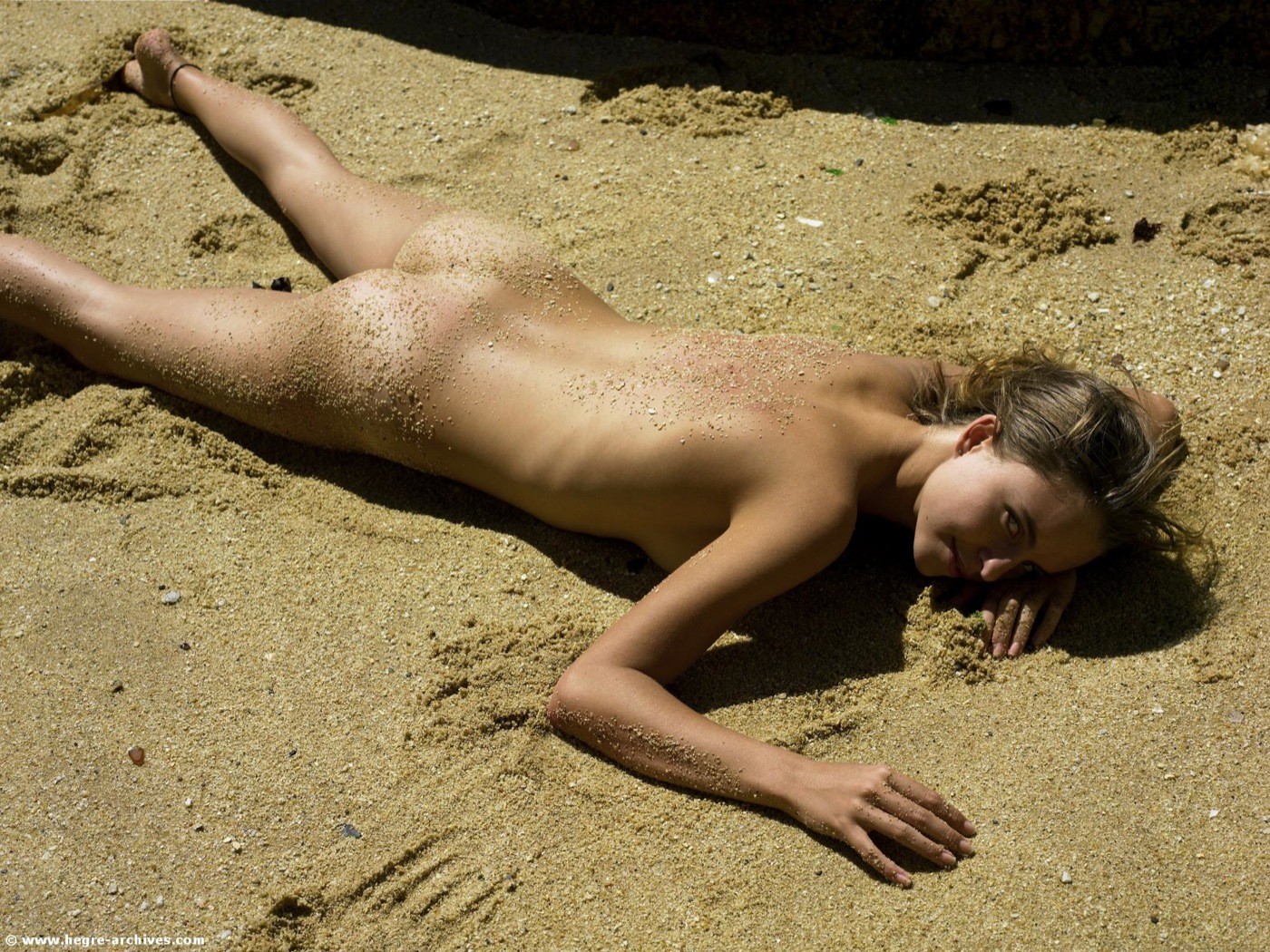 Чика с волосатой киской голая загорает на песке - фото